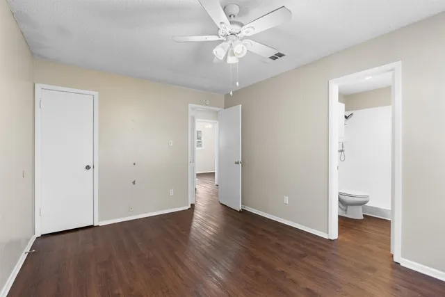 an empty room with wooden floor and a ceiling fan