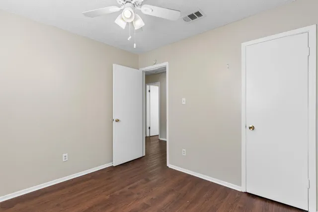an empty room with wooden floor and ceiling fan