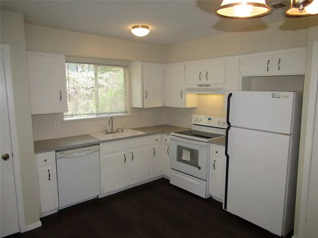 a kitchen with granite countertop white cabinets and white appliances