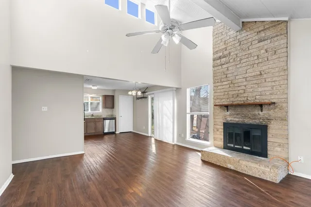 a view of an empty room with wooden floor fireplace and a window
