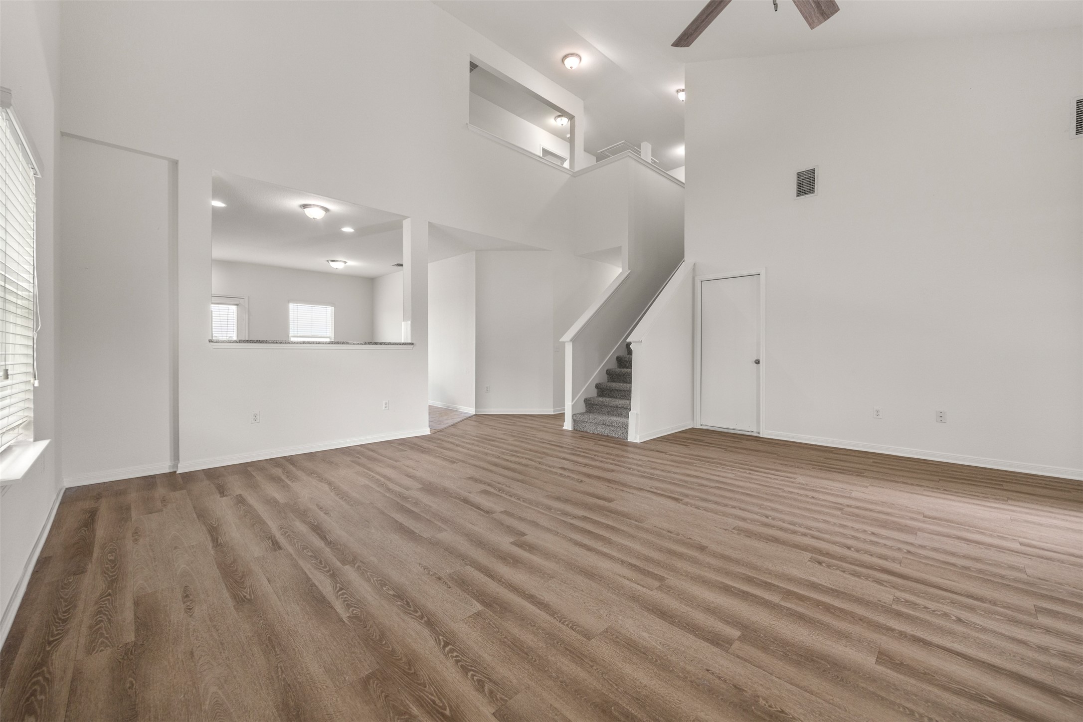 703 Liard River Road Hutto, TX 78634 - Photo 5 of 16 A spacious living area features high ceilings, wood-look flooring, and a view into the kitchen from a pass-through window.