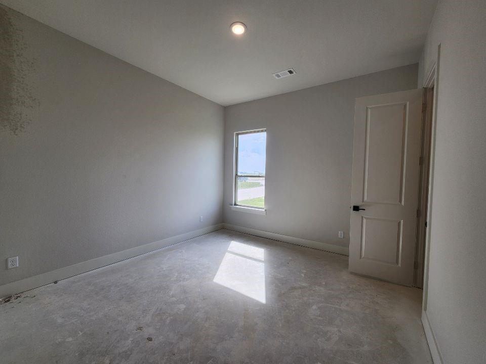 2305 Gypsum Street Krum, TX 76249 - Photo 19 of 22 Bright interior space featuring a single window, white paneled door with black hardware, and an overhead flush-mount light fixture