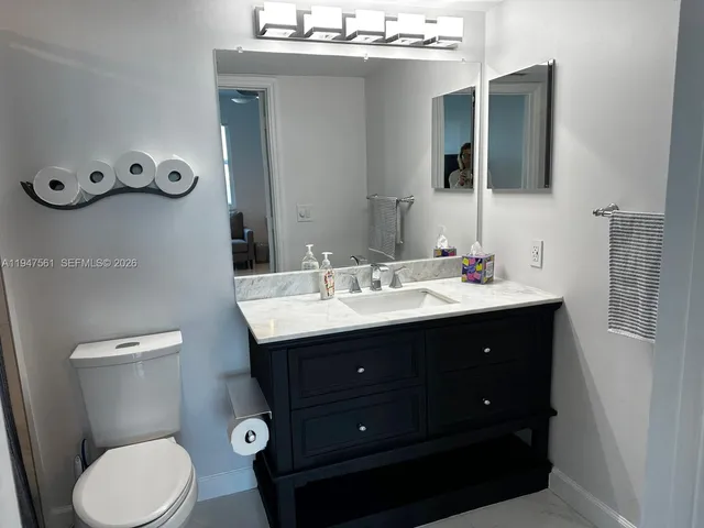 a bathroom with a sink vanity mirror and toilet