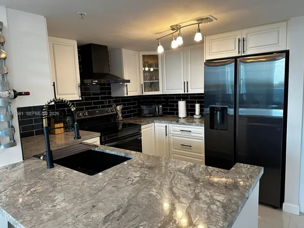 a kitchen with stainless steel appliances kitchen island granite countertop a refrigerator a sink a stove and dishwasher