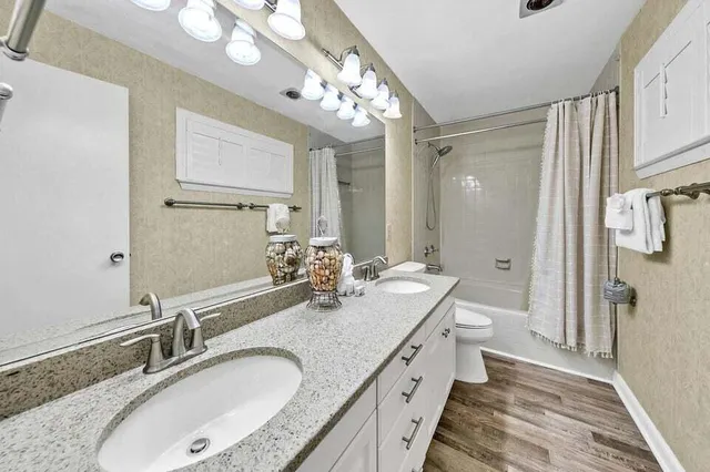 a bathroom with a granite countertop double vanity sink mirror and shower