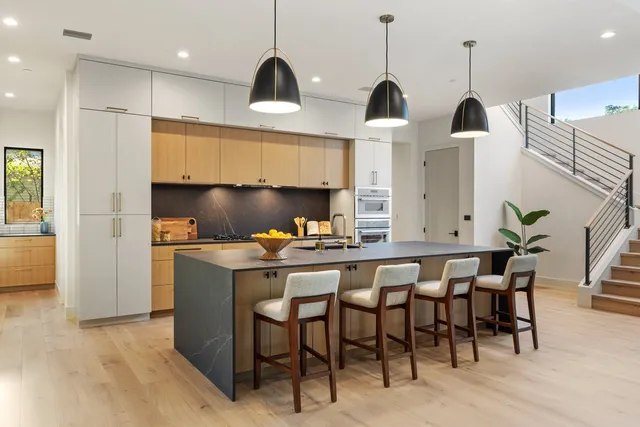 a kitchen with stainless steel appliances a dining table chairs and white cabinets