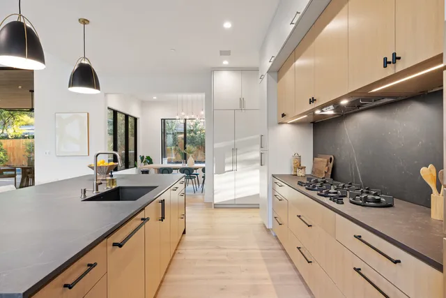 a large kitchen with stainless steel appliances a sink a stove and a wooden floors