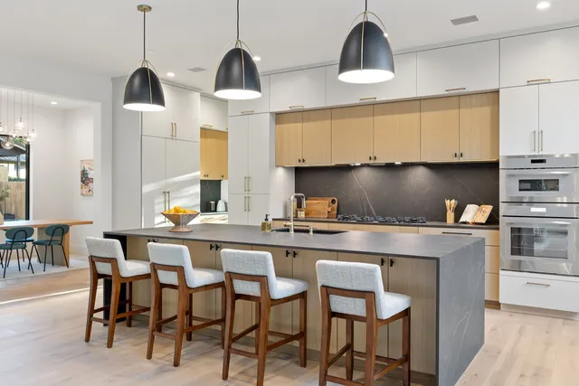 a kitchen with stainless steel appliances a dining table chairs and white cabinets