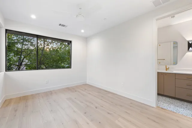 a view of an empty room with a window and wooden floor
