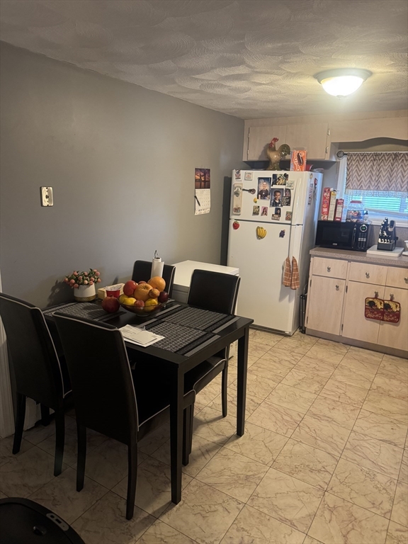 21 Cook, Unit 1 Chelsea, MA 02150 - Photo 2 of 32 a kitchen with a table chairs and a refrigerator
