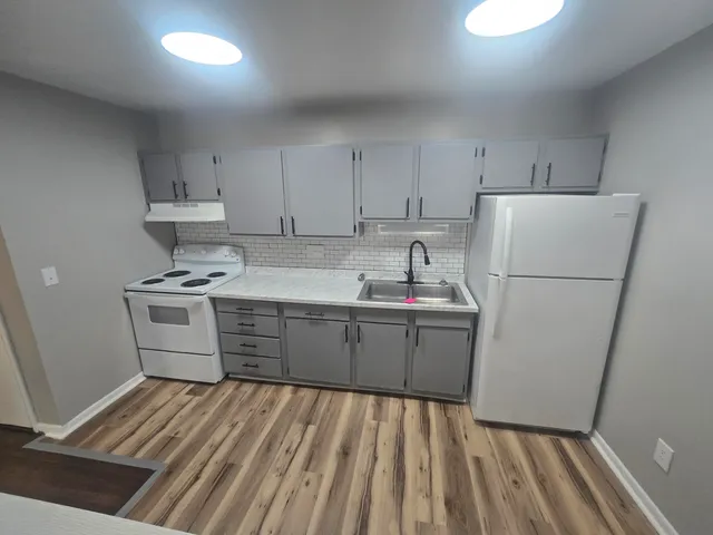 a kitchen with sink a refrigerator and white cabinets