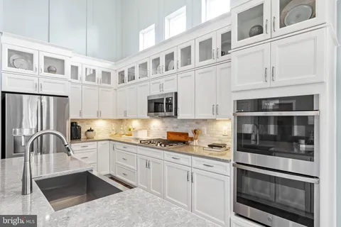 a kitchen with stainless steel appliances granite countertop white cabinets and a stove