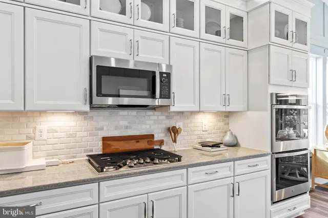 a kitchen with stainless steel appliances granite countertop a refrigerator a stove and a sink with wooden cabinets