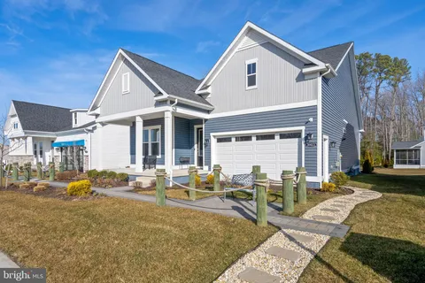a view of a white house with swimming pool lawn chairs and wooden fence