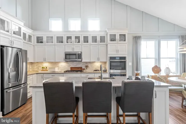 a kitchen with stainless steel appliances granite countertop a stove a refrigerator a sink a dining table and chairs