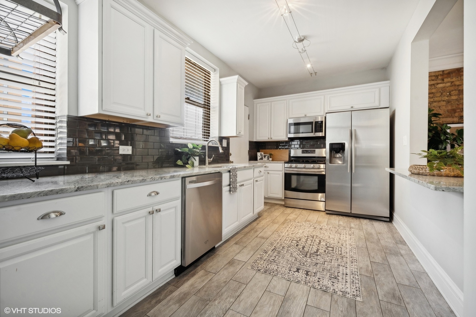 3749 North Pine Grove Avenue, Unit 3 Chicago, IL 60613 - Photo 12 of 18 a kitchen with white cabinets and stainless steel appliances
