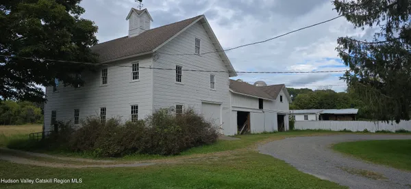 a view of a white house next to a yard with large trees