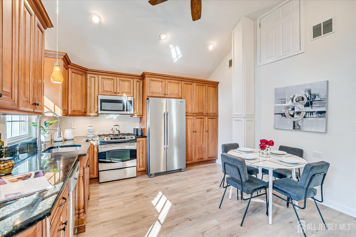 341 Victor Place Neptune, NJ 07753 - Photo 16 of 45 a open kitchen with stainless steel appliances granite countertop a stove a refrigerator a sink a dining table and chairs with wooden floor
