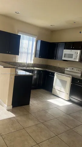 a kitchen with kitchen island granite countertop a sink and a stove