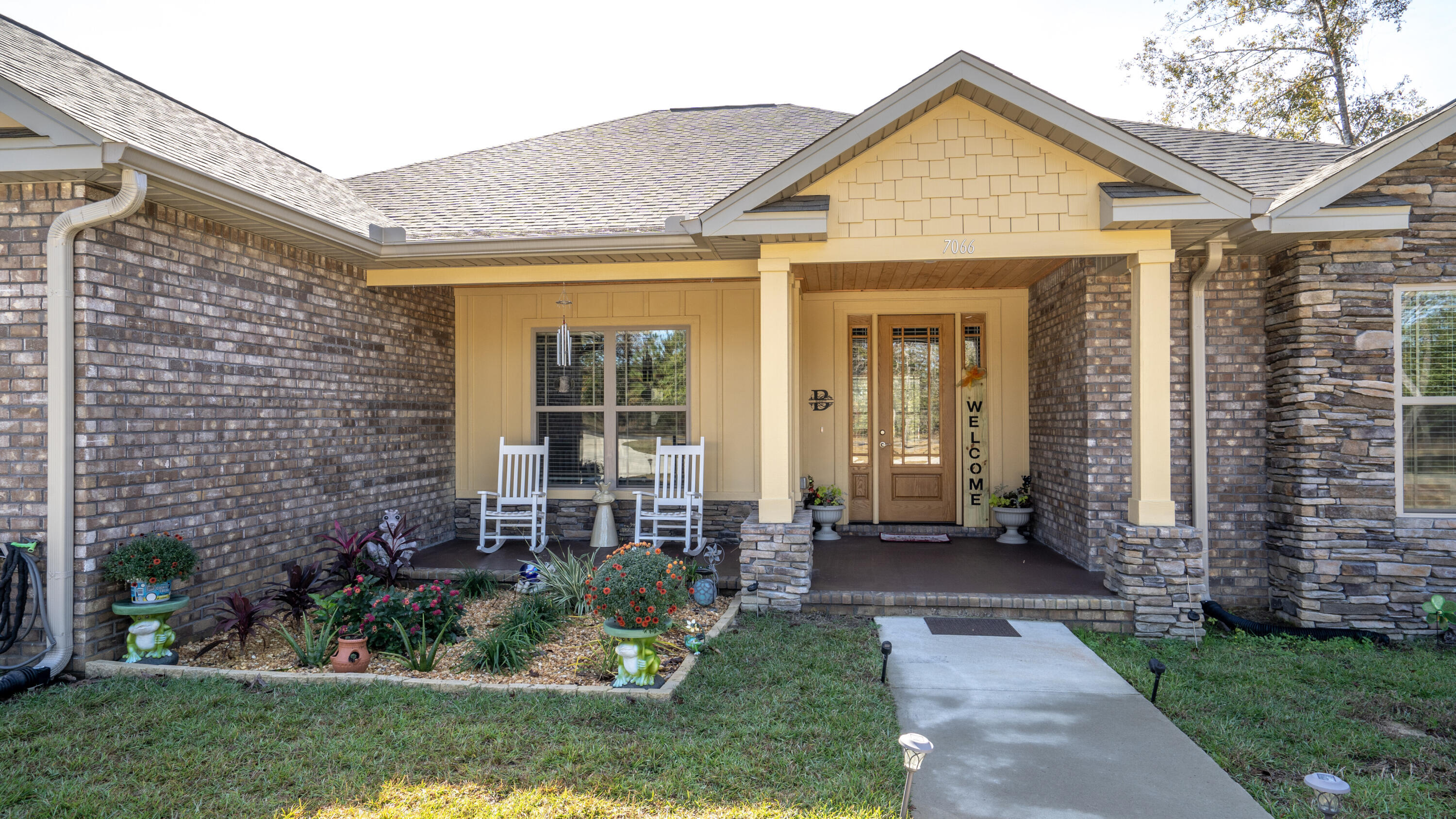 7066 Senterfitt Road Laurel Hill, FL 32567 - Photo 4 of 59 a view of a brick house with a yard potted plants and a table