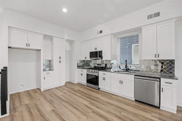 a view of a kitchen with wooden floor and electronic appliances