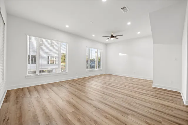 an empty room with a window and a ceiling fan