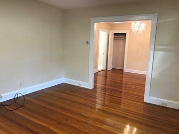 139 Pine Street, Unit 1/F Quincy, MA 02170 - Photo 2 of 10 a view of an empty room with wooden floor and a window