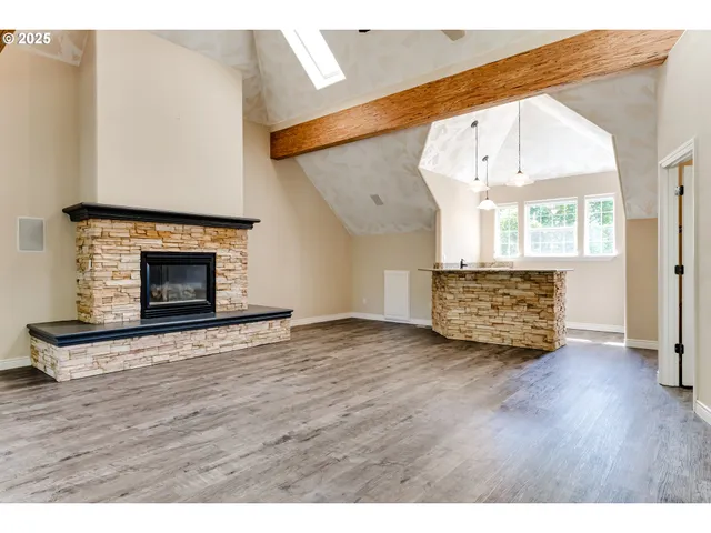 a view of an empty room with wooden floor fireplace and a window