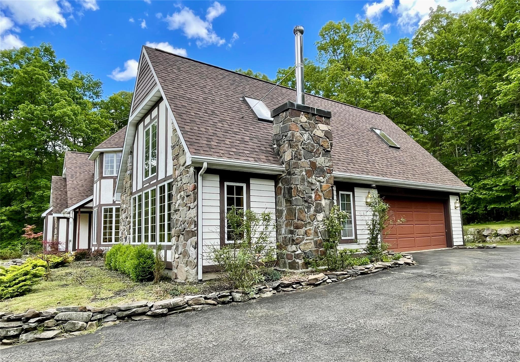 71 Saddleback Ridge Wallkill, NY 12589 - Photo 26 of 39 View of front of property featuring roof with shingles, an attached garage, asphalt driveway, stone siding, and a chimney