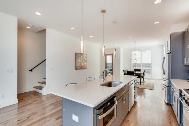 a kitchen with stainless steel appliances a sink a stove a refrigerator and white cabinets with wooden floor