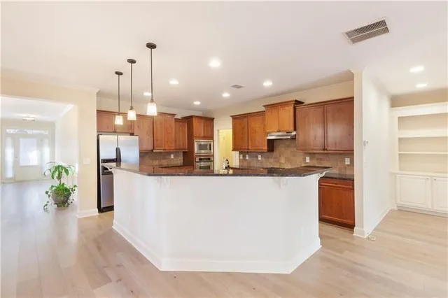 a kitchen with stainless steel appliances granite countertop a sink refrigerator and cabinets