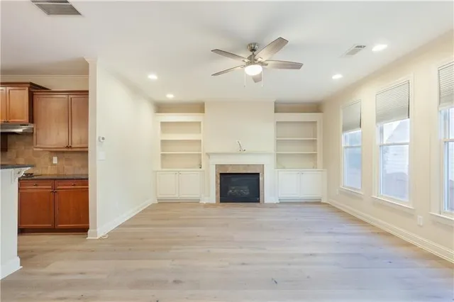 a kitchen with stainless steel appliances granite countertop a refrigerator a sink dishwasher a stove and white countertops with wooden floor