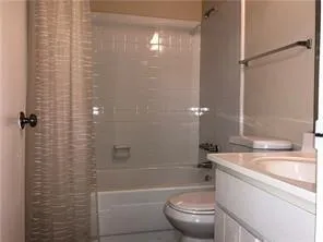 a bathroom with a granite countertop bathtub shower sink vanity and toilet