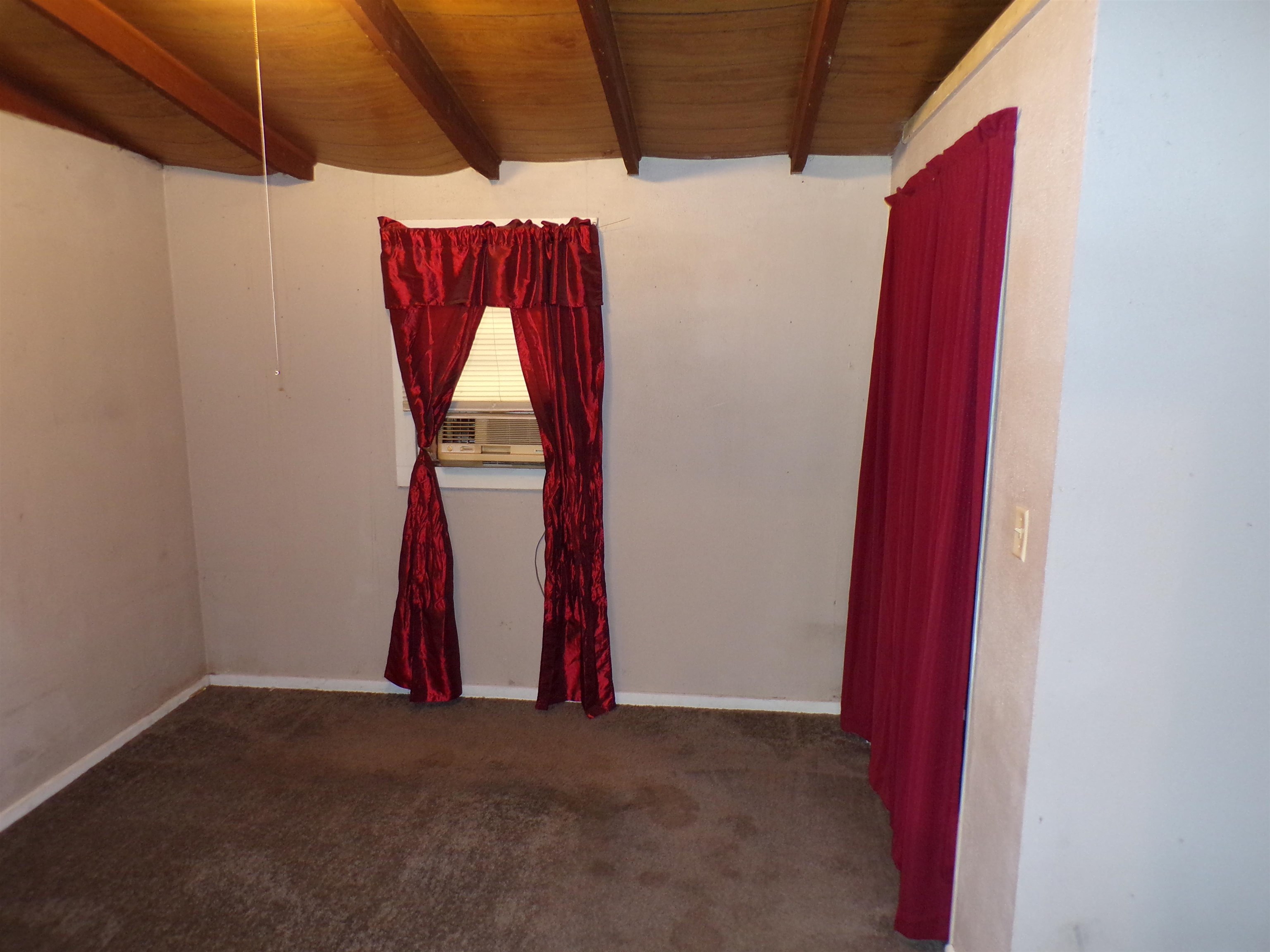 35 Cr 341 Road Iuka, MS 38852 - Photo 10 of 15 Room featuring exposed wood ceiling beams, a window with horizontal blinds, and a wall-mounted air conditioning unit