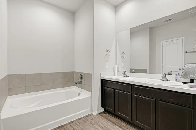 a bathroom with a tub sink and mirror