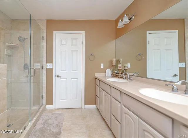 a bathroom with a double vanity sink mirror and shower