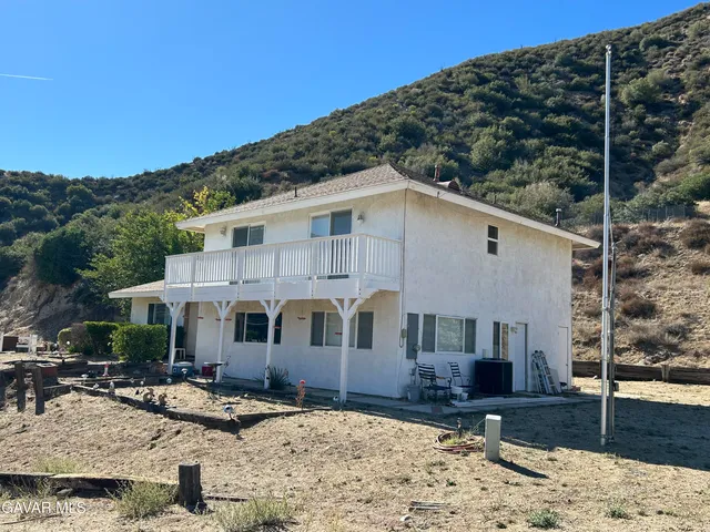a view of a white house with a large tree