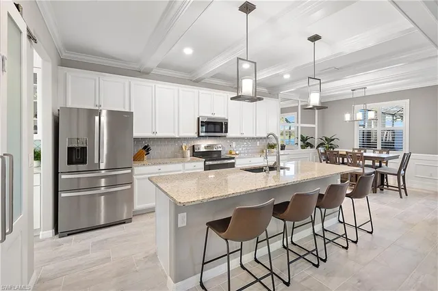 a kitchen with stainless steel appliances a table chairs refrigerator and chairs