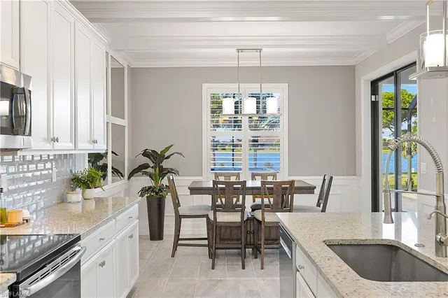 a kitchen with kitchen island granite countertop a stove a sink a refrigerator and white cabinets with wooden floor