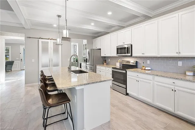 a kitchen with stainless steel appliances granite countertop a stove a sink a microwave a refrigerator and white cabinets