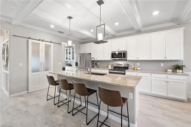 a kitchen with stainless steel appliances granite countertop a sink a stove a refrigerator cabinets and chairs