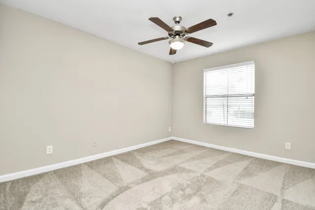 an empty room with a ceiling fan and a window