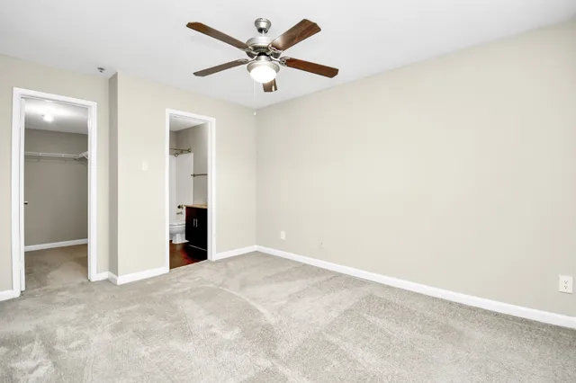 an empty room with a chandelier fan and closet area
