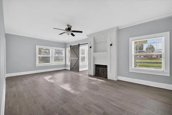a view of an empty room with a window and wooden floor