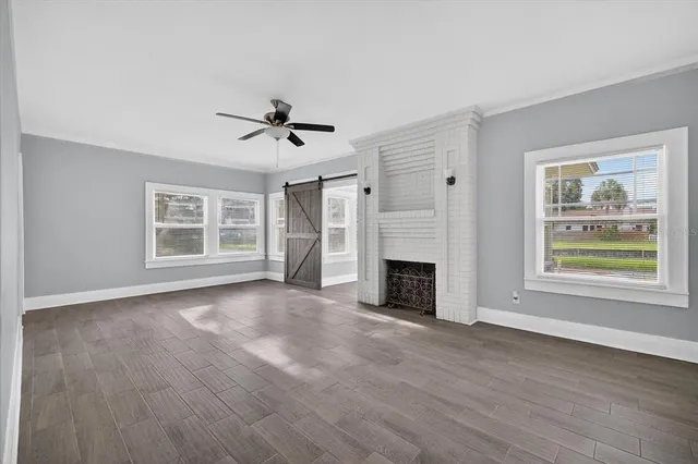 a view of an empty room with a window and wooden floor