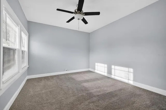 an empty room with windows and fan