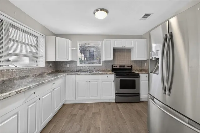 a kitchen with granite countertop a sink stove and cabinets
