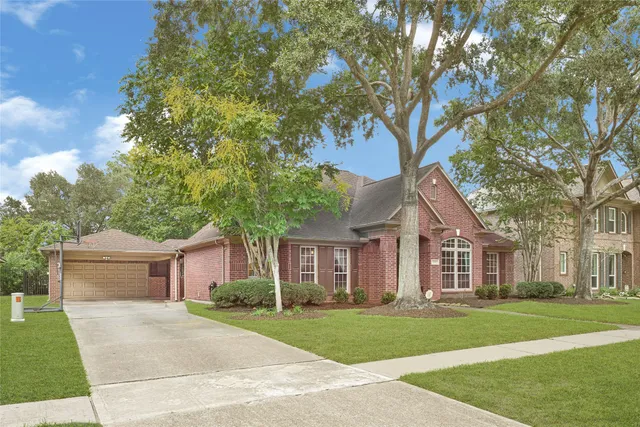a front view of a house with a garden and trees