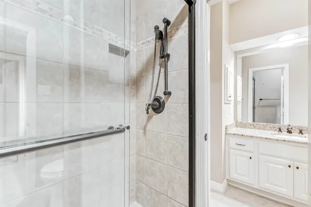 a bathroom with a granite countertop shower a sink and a mirror