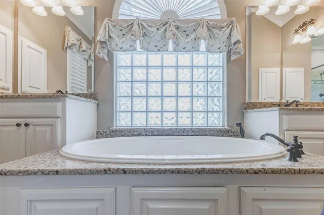 a bathroom with granite countertop a sink and a bathtub